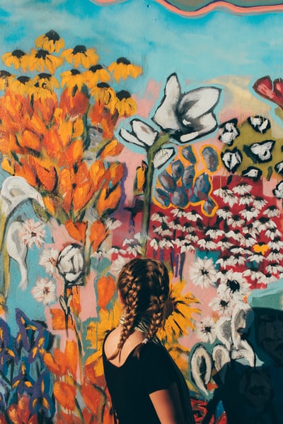 女人面对前面的花涂鸦墙
